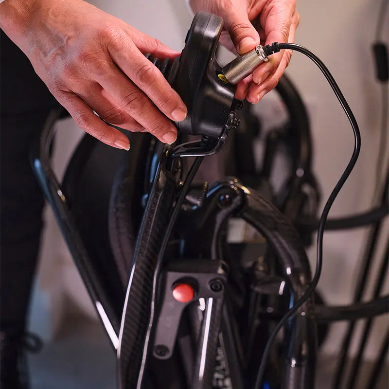 Close-up of hands connecting a cable to a Quickie Q50 R Carbon Folding Powerchair electrical system