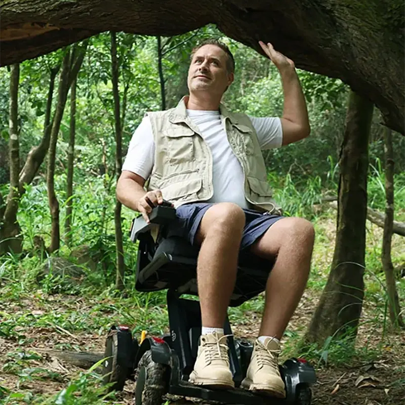 Man riding a Mobility World Ltd UK: XSTO M4 Electric Powered Wheelchair in a forest setting