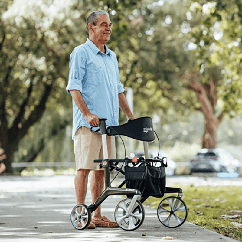 Man using an aspire ninja carbon fibre lightweight seat walker rollator in a park setting