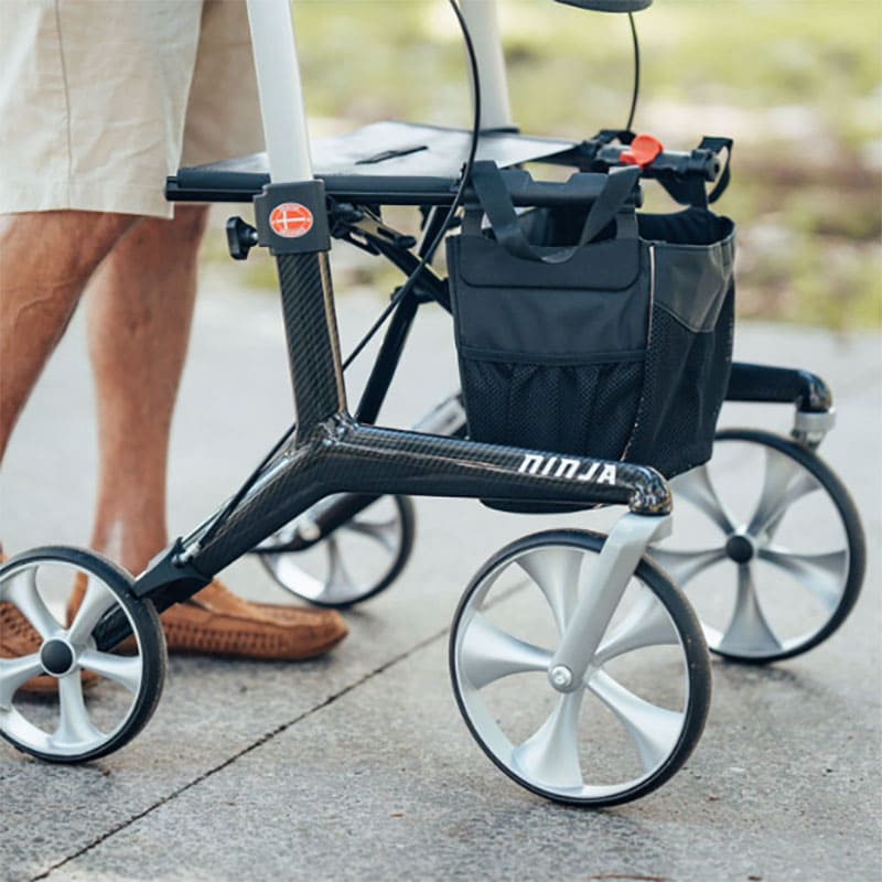Close-up of a rollator with Aspire Ninja carbon fibre lightweight seat walker on a sidewalk.