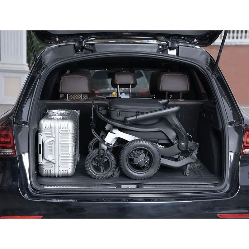 Car trunk with a folded Robooter E80 Ultra Carbon Fiber Lightweight Folding Powerchair and a suitcase inside