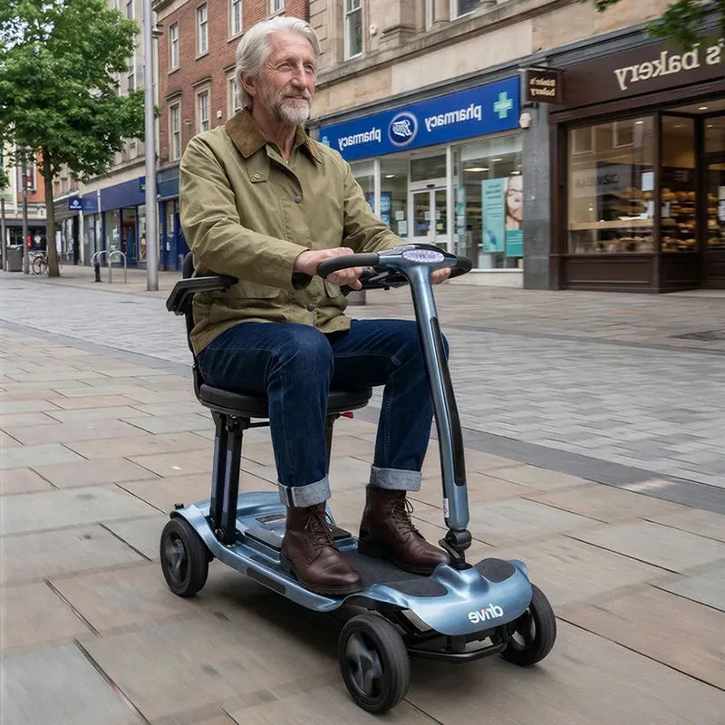 Man riding AeroMg Lightweight Folding Mobility Scooter on a city street with shops in the background