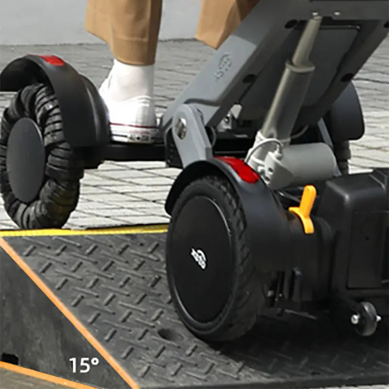 Close-up of a XSTO M4 Electric Powered Wheelchair on a ramp with a person's foot wearing a white shoe.
