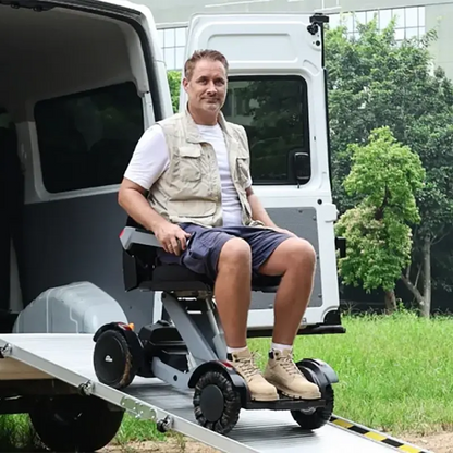 Man using an XSTO M4 Electric Powered Wheelchair with a ramp attached to a van in an outdoor setting.